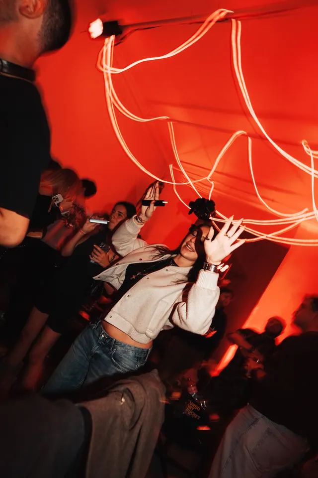 Dancers raising their arms beneath glowing ribbons