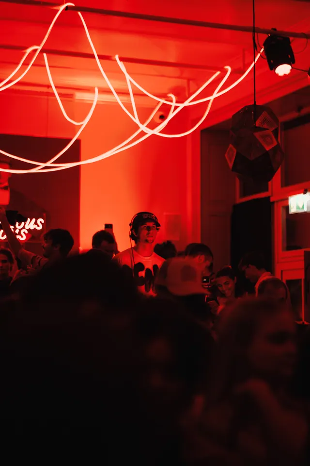 The DJ booth and crowd beneath a light installation