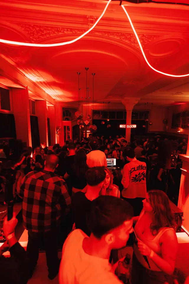 A packed dance floor under red lights